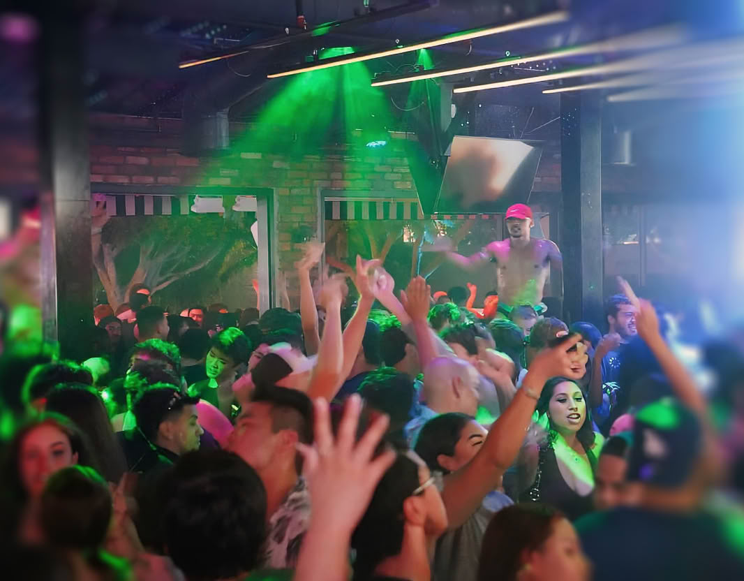 Two young adults enjoying drinks and music in a vibrant nightclub setting with red lighting.